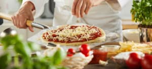 Cheese lock - Chef sprinkling mozzarella cheese onto a raw pizza