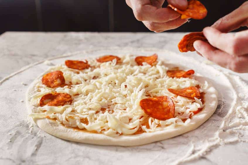 Placing Pepperoni on pizza