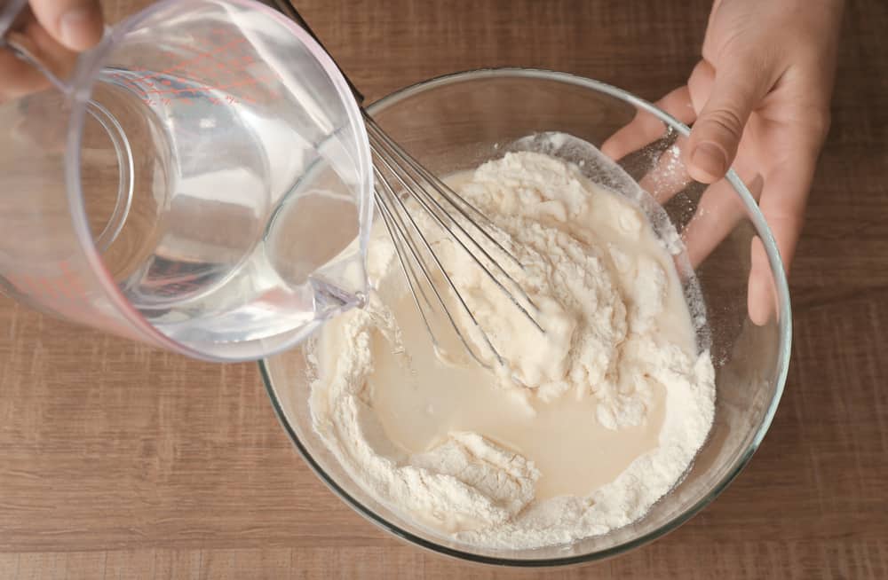 Pouring Water into flour in a bowl