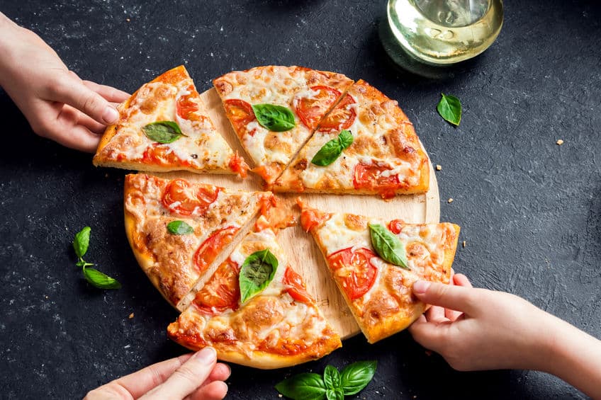 Hands holding slice of margharita pizza