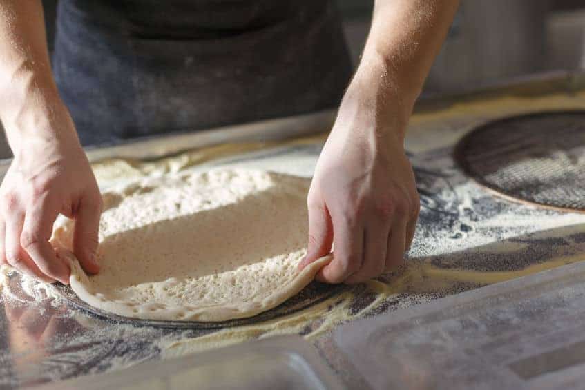 placing pizza dough on screen
