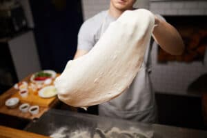 stretching pizza dough with back of hands